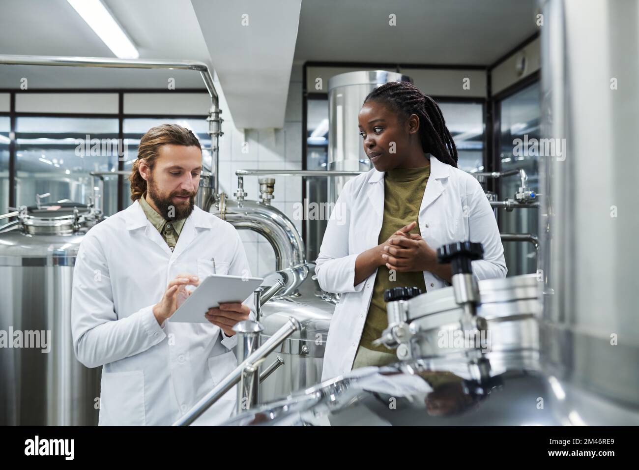 Les technologues de brasserie utilisent une application sur une tablette pour contrôler le travail de l'équipement Banque D'Images