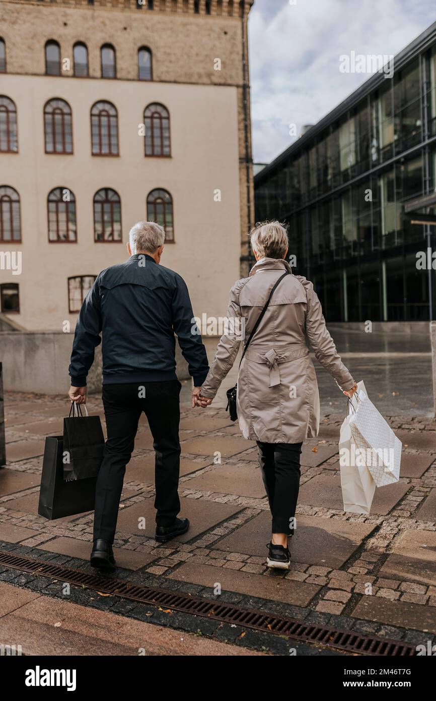 Couple marchant dans la ville avec des sacs de shopping Banque D'Images