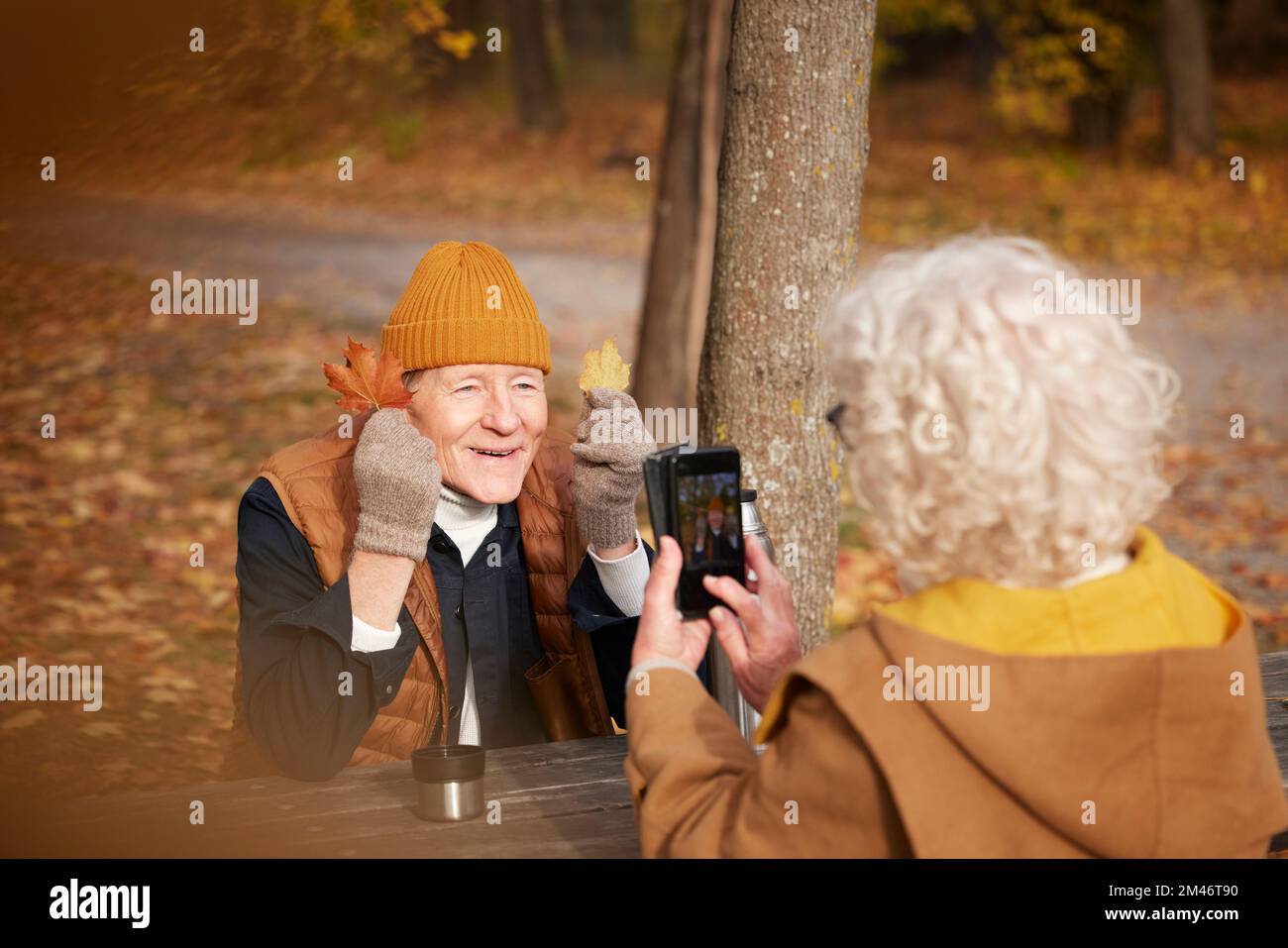 Femme senior photographiant son partenaire dans le parc Banque D'Images