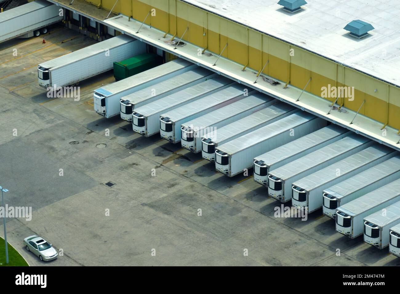 Vue de dessus du centre logistique géant avec de nombreux camions de remorques commerciales qui déchargent et chargent des produits de vente au détail pour une expédition ultérieure. Économie mondiale Banque D'Images