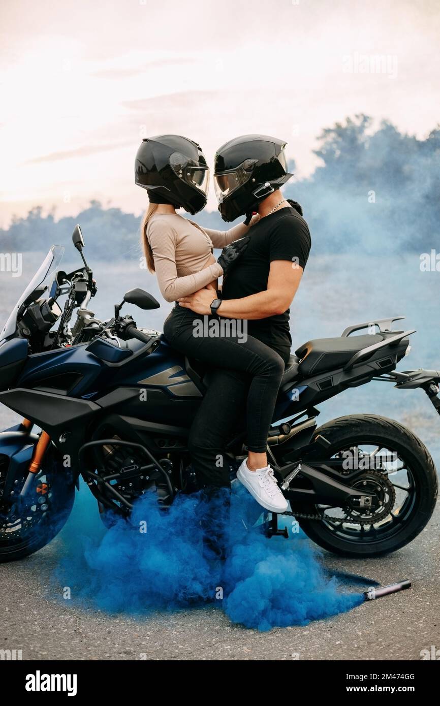 Homme et femme en casques de moto près de la moto avec fumée colorée Photo  Stock - Alamy