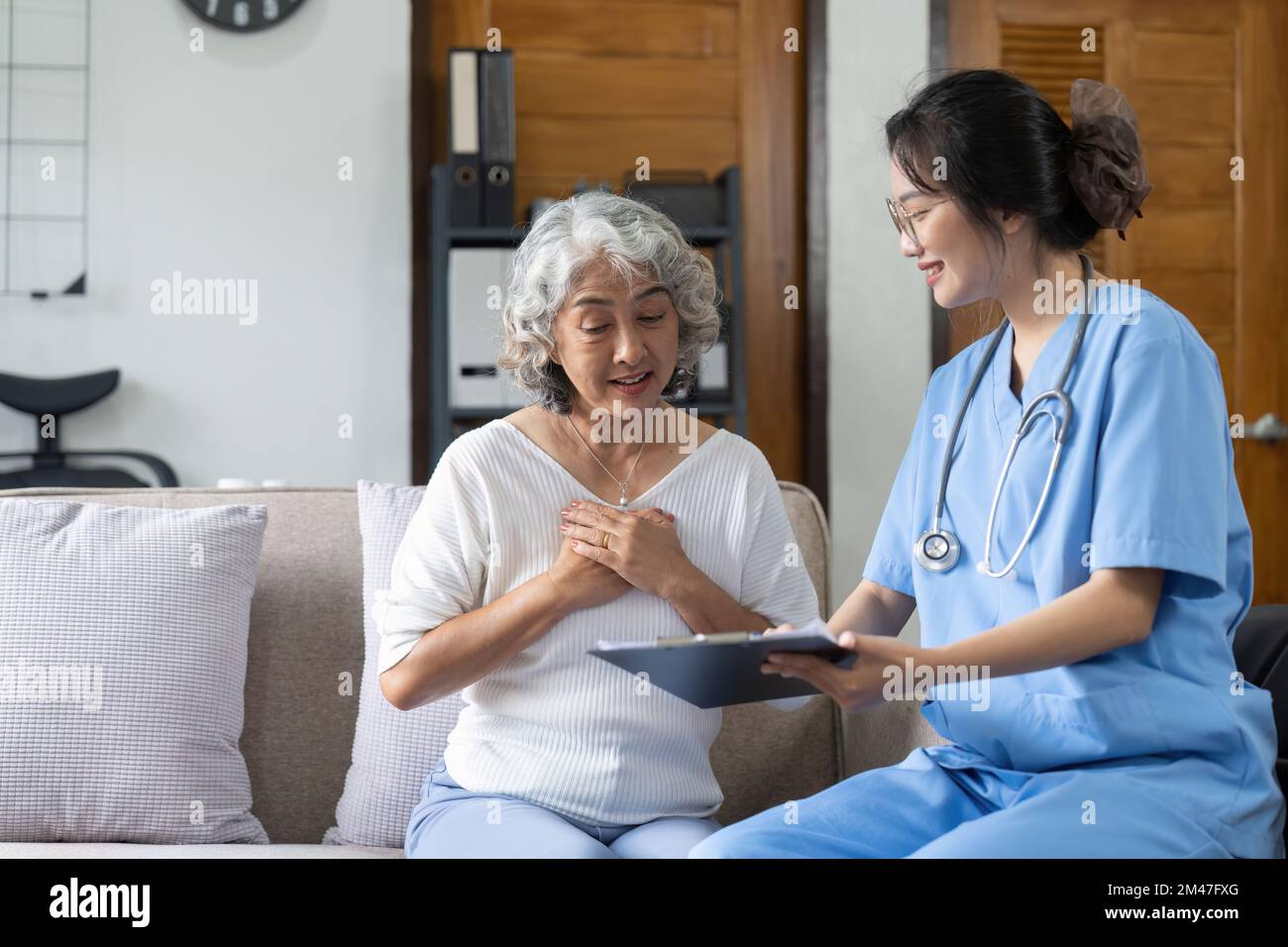 Jeune infirmière asiatique, aide à la vie, soignant à domicile ou médecin, visite d'un ancien citoyen âgé à domicile parler de la liste de contrôle de suivi des résultats Banque D'Images