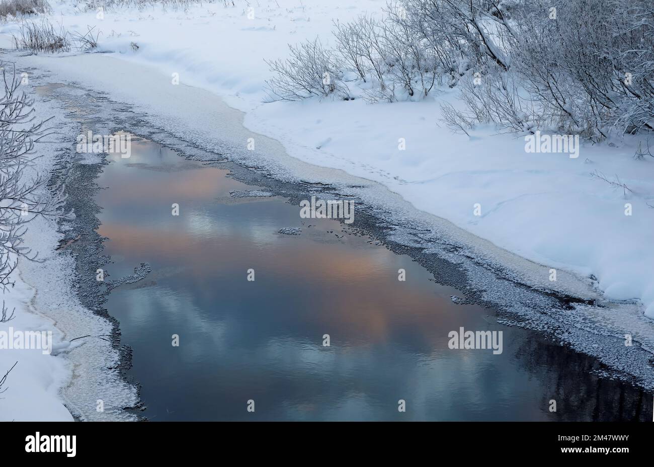 Bord de glace dans l'eau avec des reflets de couleurs sombres du ciel Banque D'Images