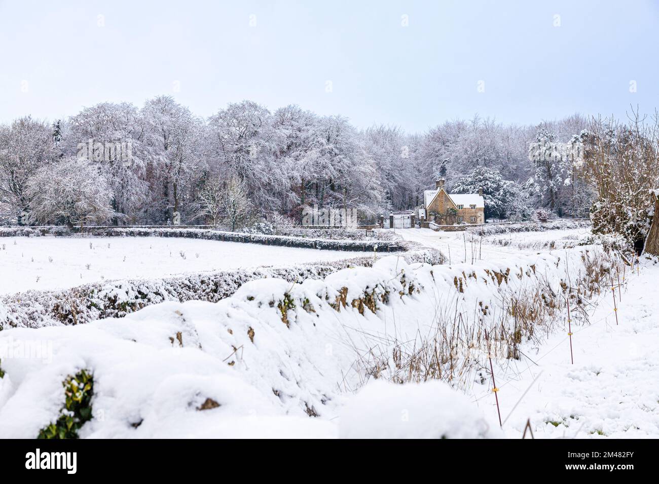 Début de l'hiver neige sur le Lodge et les portes de Miserden Park près du village de Cotswold de Winstone, Gloucestershire, Angleterre Royaume-Uni Banque D'Images