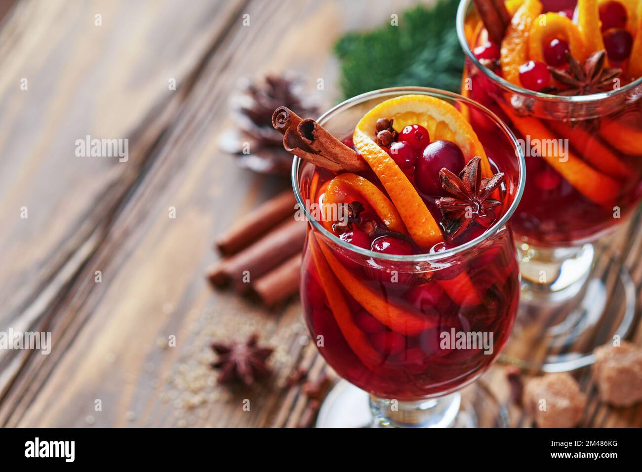 Vin chaud chaud chaud de Noël. Verres de vin chaud aux épices aromatiques cannelle, anis, sucre et branches de sapin avec bokeh et décorations. Trait Banque D'Images