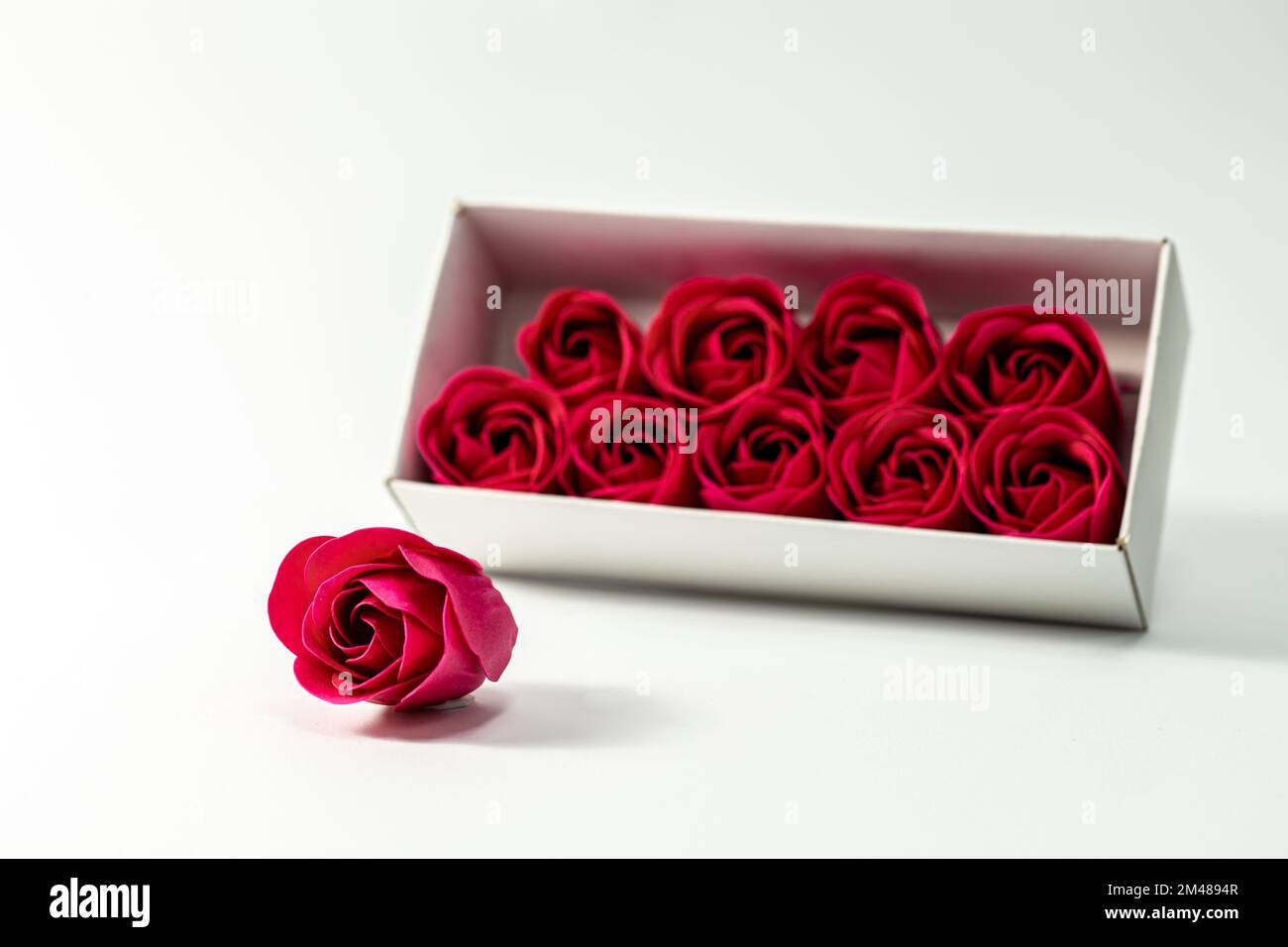Boîte avec roses rouges décoratives sur un fond blanc isolé. Banque D'Images