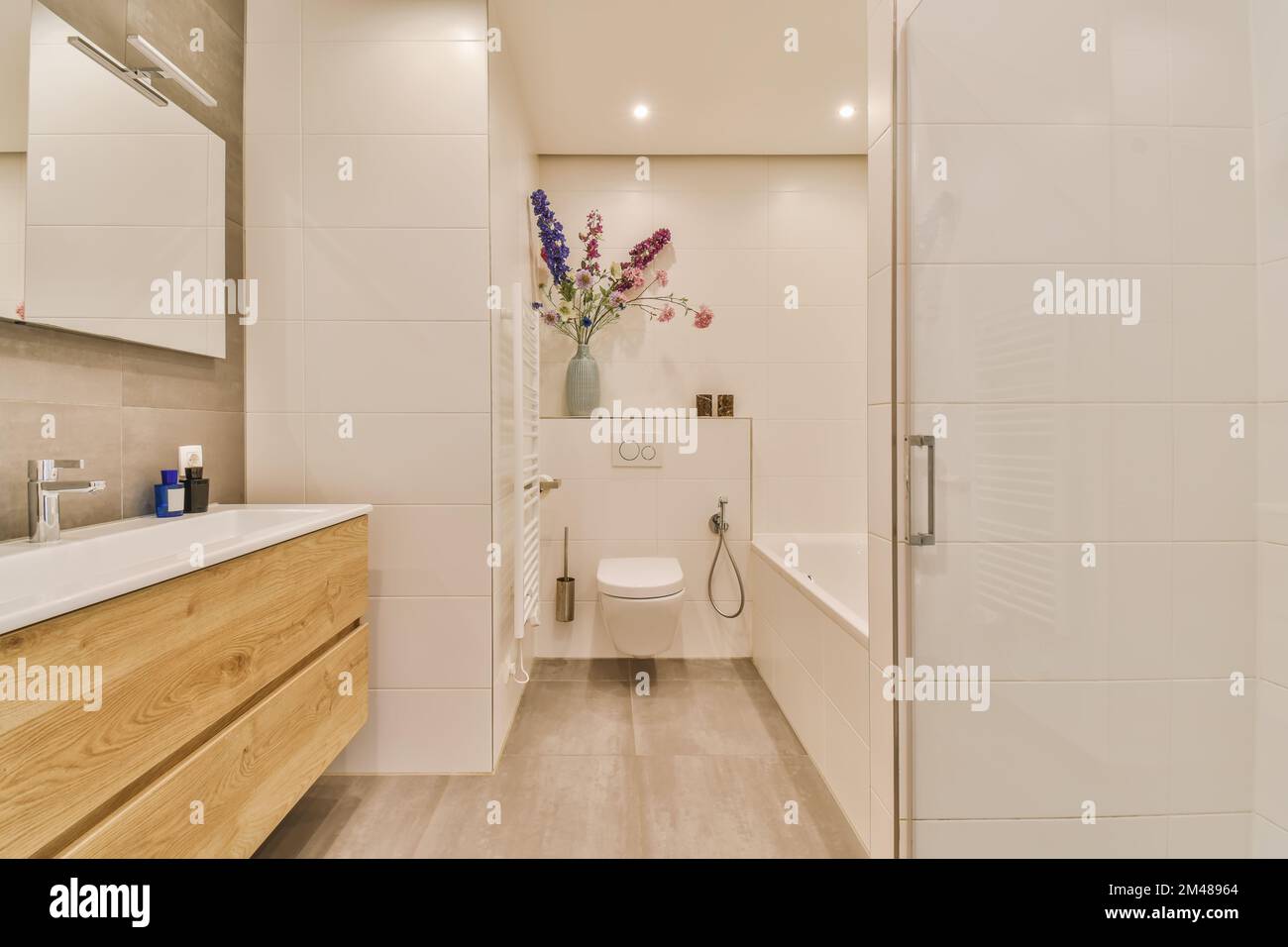 une salle de bains moderne avec parquet et murs blancs, ainsi qu''une coiffeuse en bois dans la cabine de douche se trouve à côté des toilettes Banque D'Images
