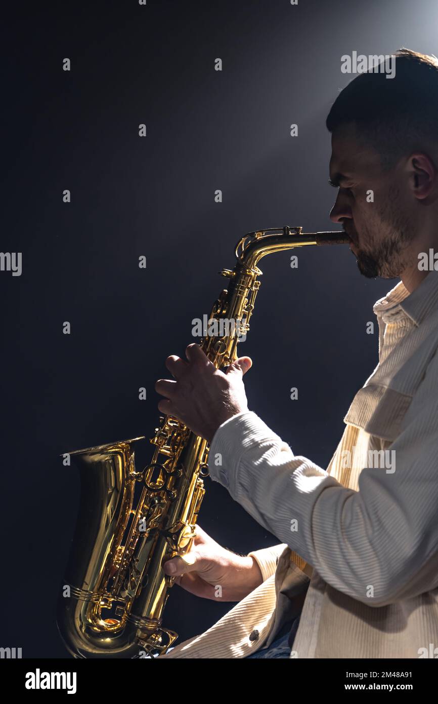 Un européen joue le saxophone dans le noir. Banque D'Images