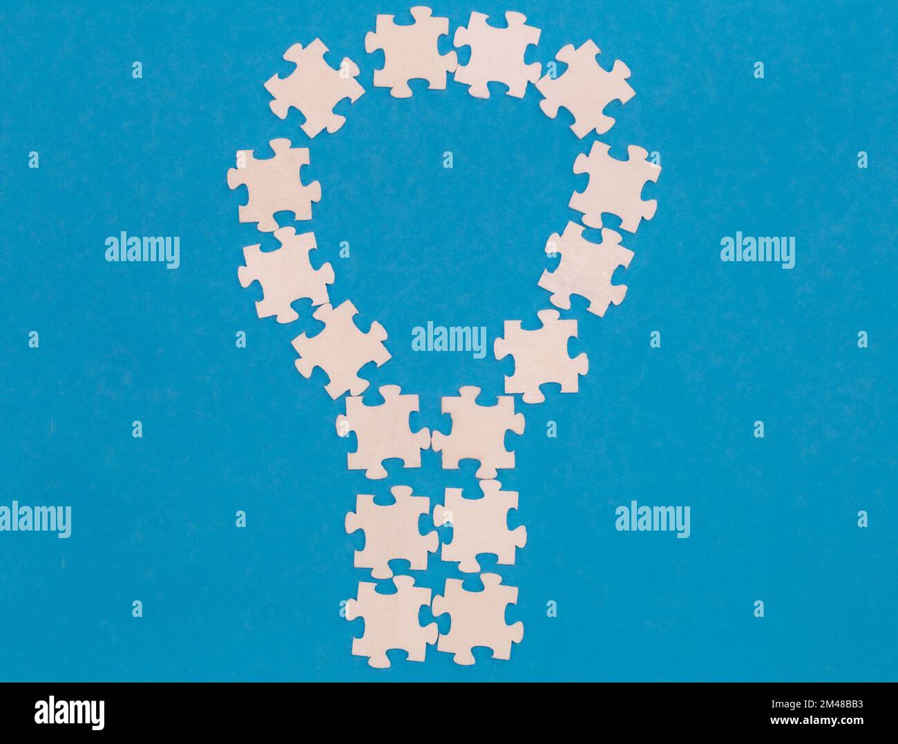 Puzzles blancs en forme d'ampoule sur fond bleu, plat. Banque D'Images