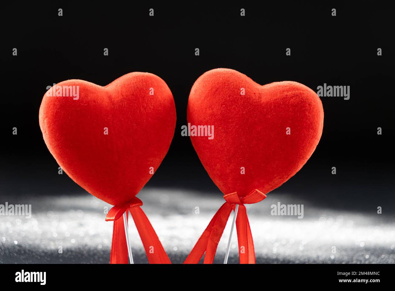 Saint-Valentin, deux coeurs rouges aimanté sur fond noir avec des paillettes. Banque D'Images