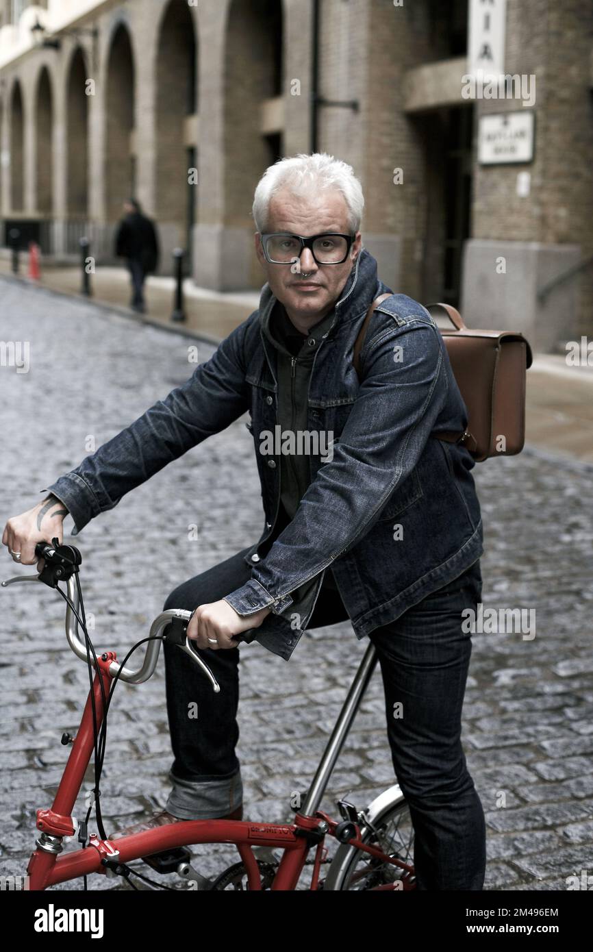 homme caucasien assis sur le vélo Brompton avec sac arrière en cuir à Londres, Royaume-Uni Banque D'Images