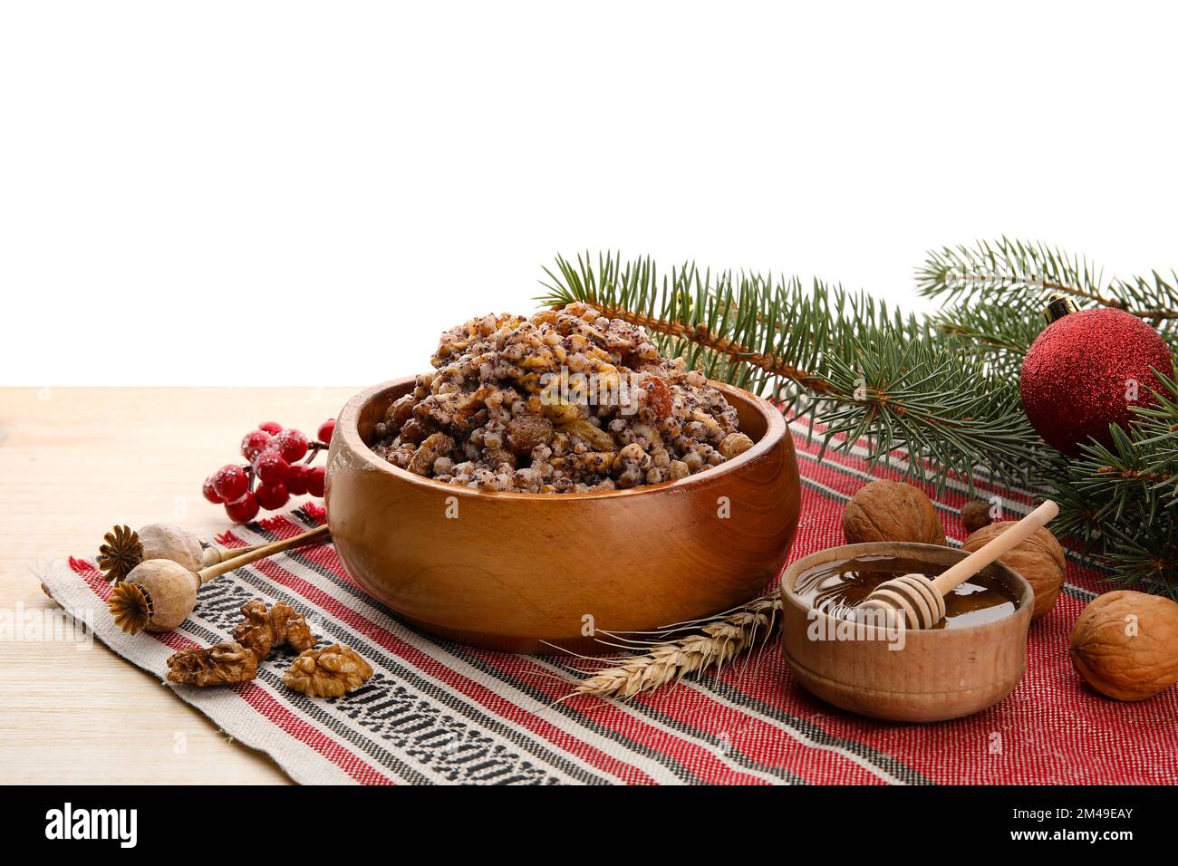 Bol de Kutya, miel, noix et branches de Noël sur table sur fond blanc Banque D'Images