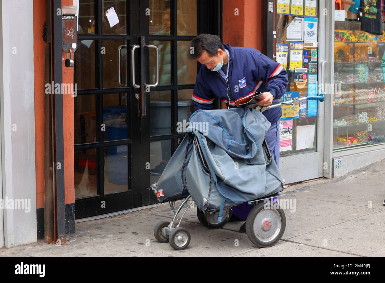Un facteur sino-américain USPS avec un chariot postal cartable à New York. Banque D'Images