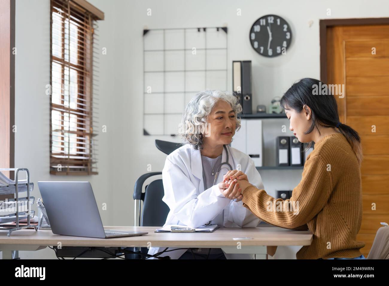 Un médecin senior tient la main de la patiente pour donner du confort, exprimer sa sympathie pour les soins de santé, aider les médecins à soutenir la confiance encourager à rassurer les patients infertiles Banque D'Images