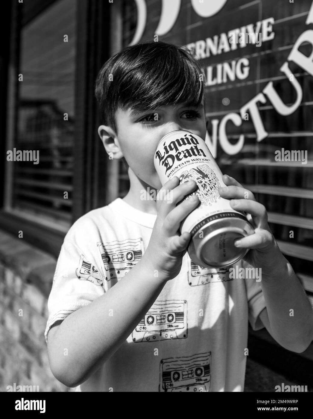 Une échelle de gris d'un enfant de garçon buvant à partir d'une bouteille de canette Banque D'Images