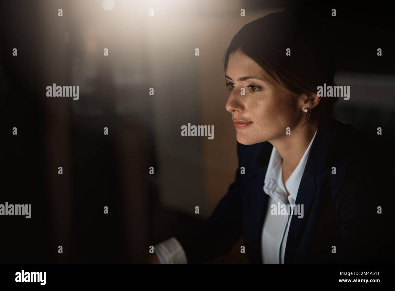Travaillez et concrétise vos efforts. une jeune femme d'affaires travaillant en ligne tard dans la nuit dans un bureau moderne. Banque D'Images