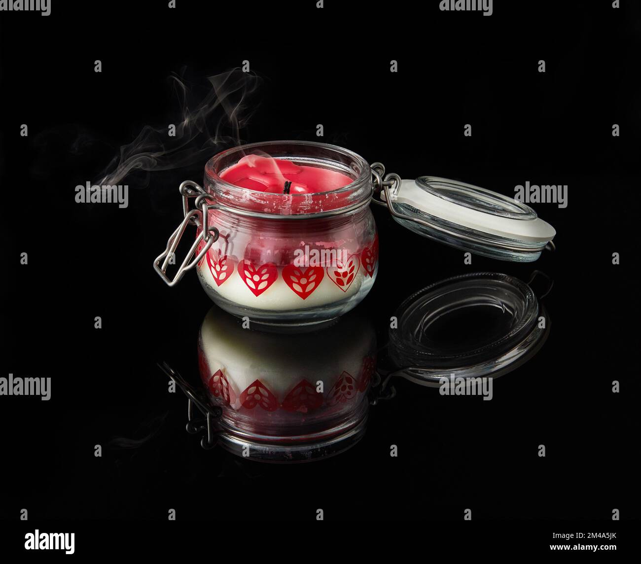 Une bougie éteinte avec fumée sur fond noir avec des arômes de vanille, de cerise, de grenade et de noix de coco Banque D'Images