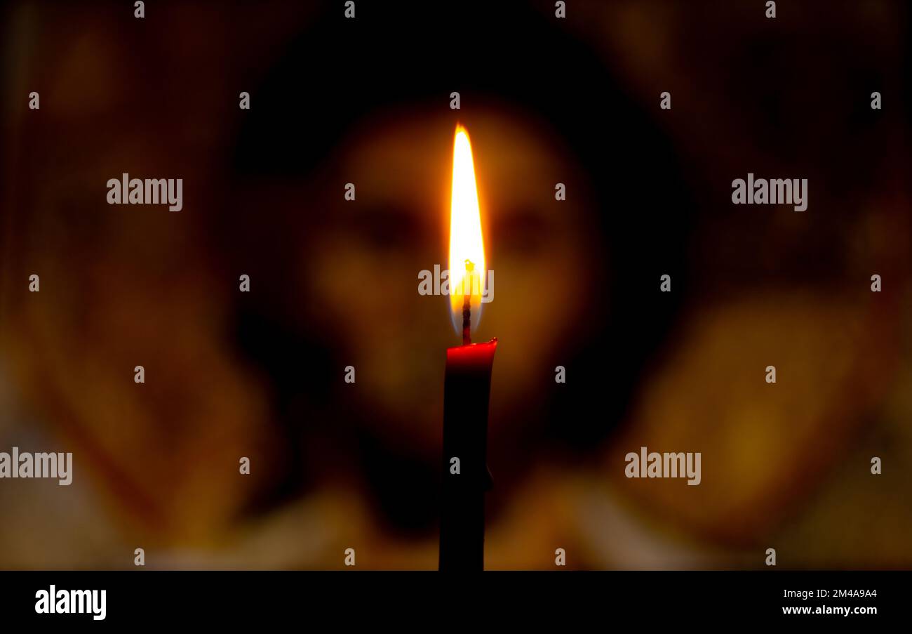 Une bougie allumée illumine l'icône de Jésus-Christ Banque D'Images