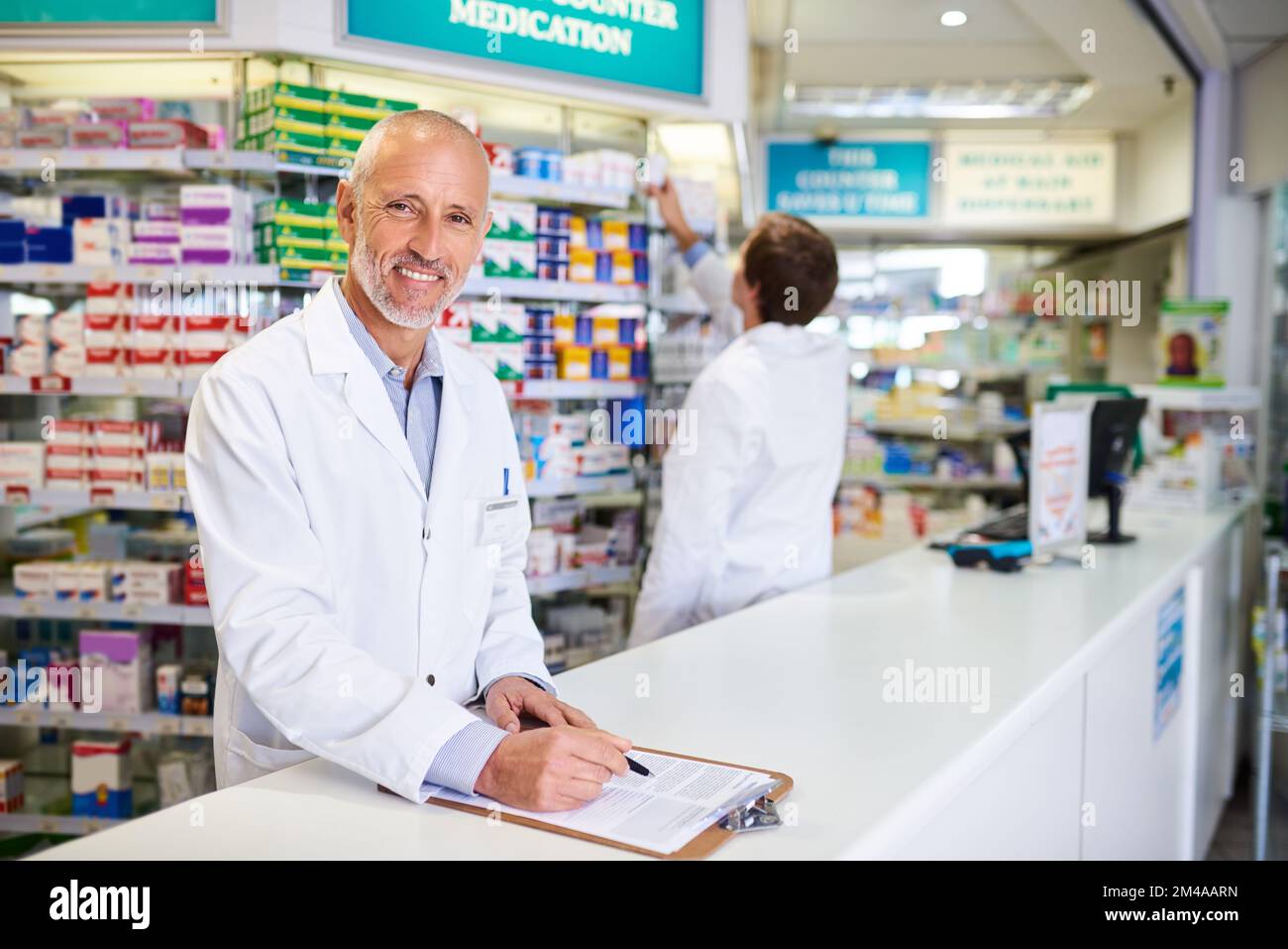 Nous devons nous assurer que nos stocks sont toujours pleins. Portrait d'un pharmacien mature écrivant sur un bloc-notes dans un chimiste. Banque D'Images