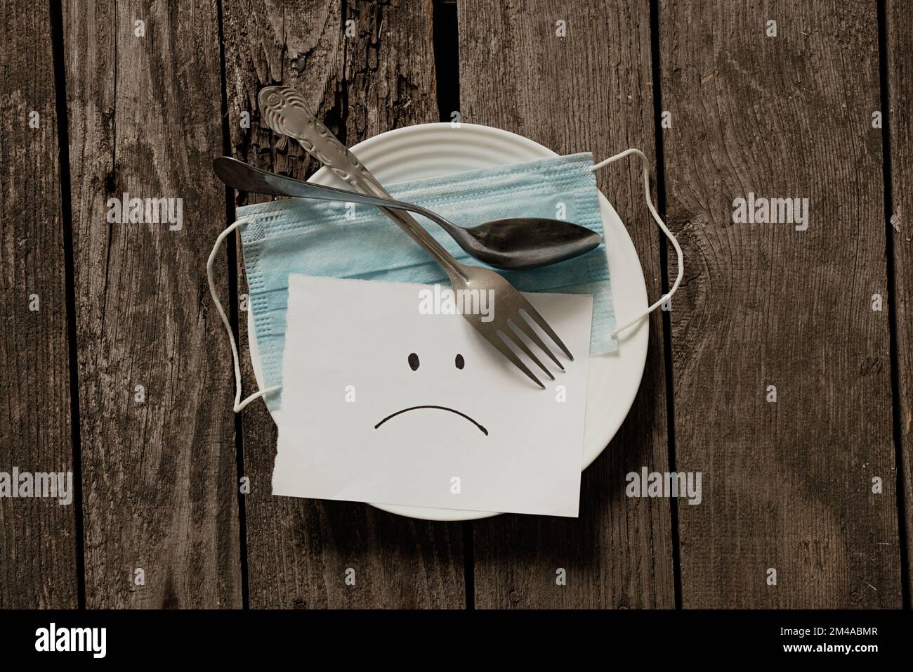 masque médical émoticône triste peint sur papier blanc sur une table Banque D'Images