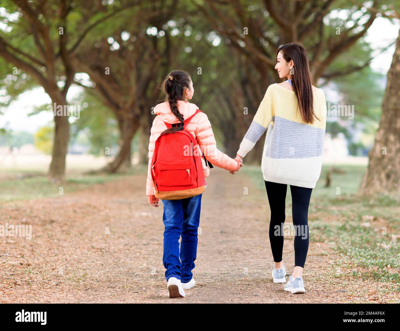 Vue arrière de la promenade de fille avec sa mère pour aller à l'école Banque D'Images