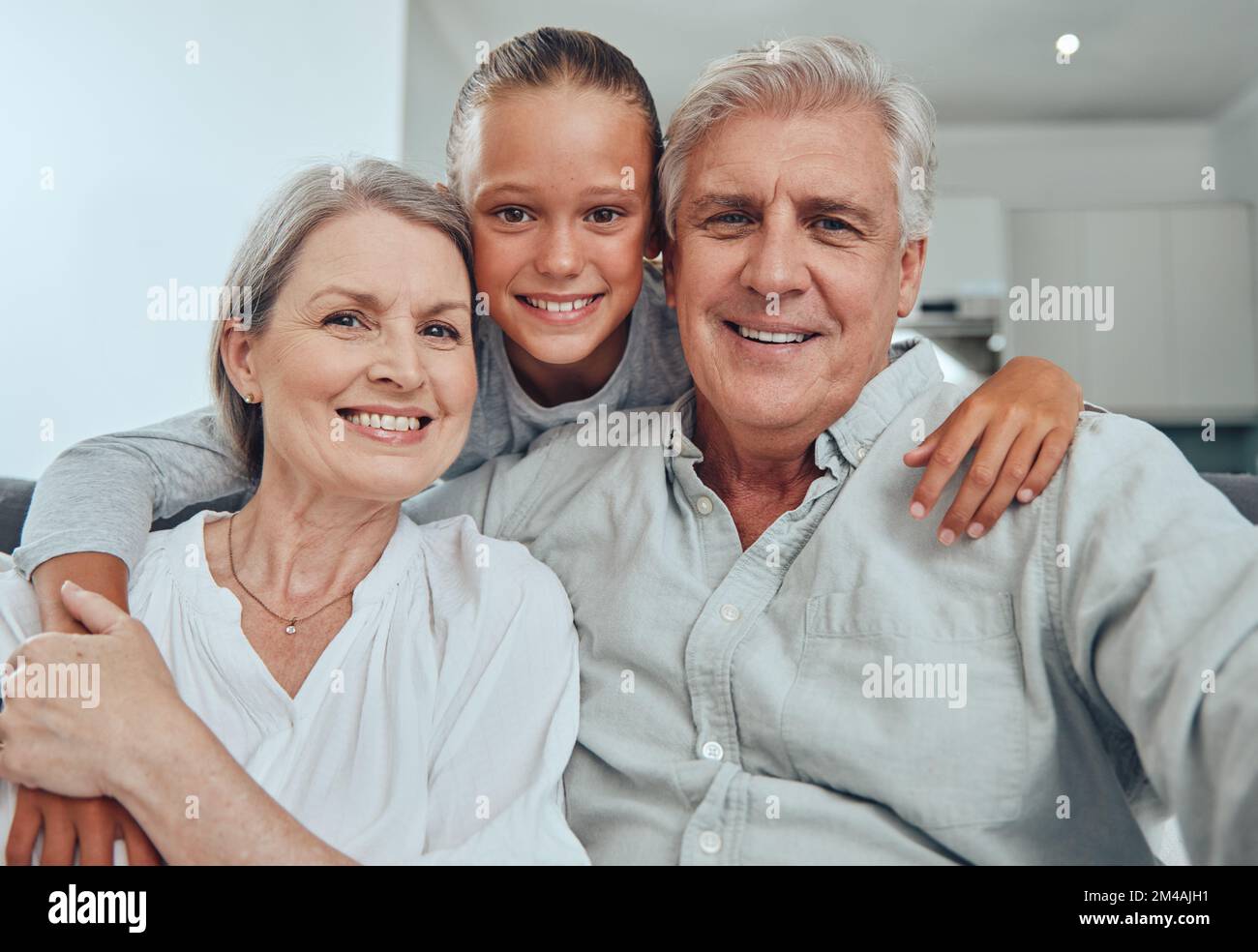 Amour, famille et portrait par fille et grands-parents sur le canapé pour lier, câlin et de qualité de temps dans leur maison ensemble. Famille, visage et homme senior heureux Banque D'Images