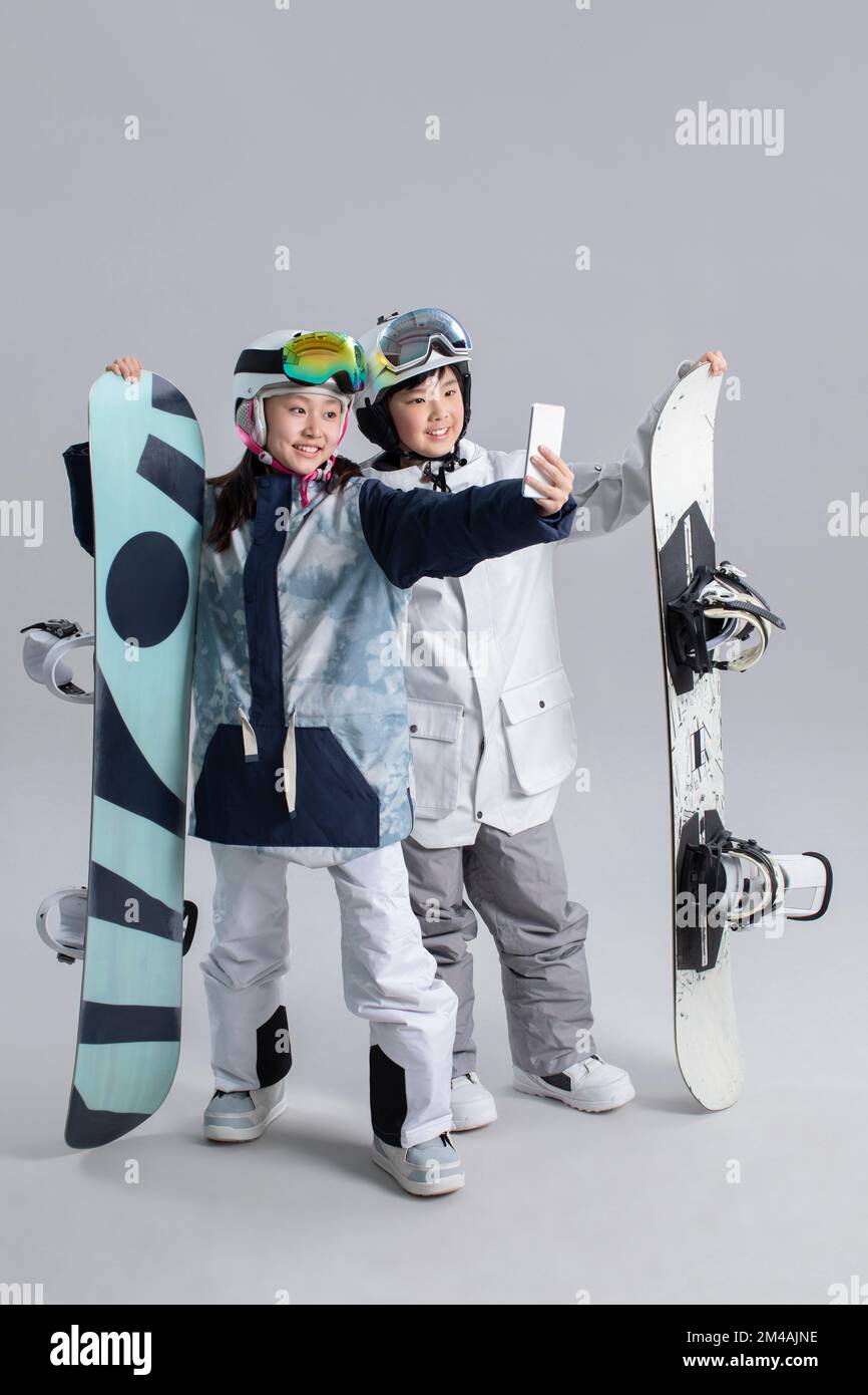 Jeune fille et garçon chinois joyeux avec des snowboards Banque D'Images