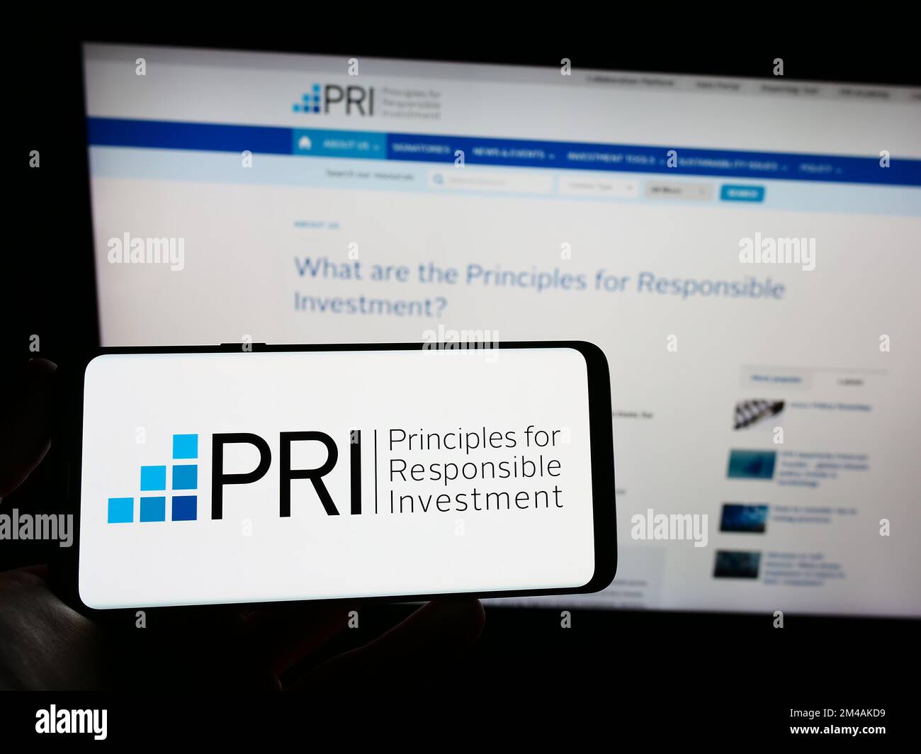 Personne portant un smartphone avec le logo des principes des Nations Unies pour l'investissement responsable (PRI) sur l'écran devant le site Web. Mise au point sur l'affichage du téléphone. Banque D'Images