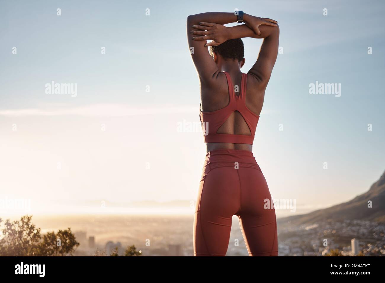 Femme noire, fitness et bras d'étirement sur la montagne pour l'exercice, l'entraînement ou l'entraînement pendant le coucher du soleil en plein air. Femme afro-américaine au chaud Banque D'Images