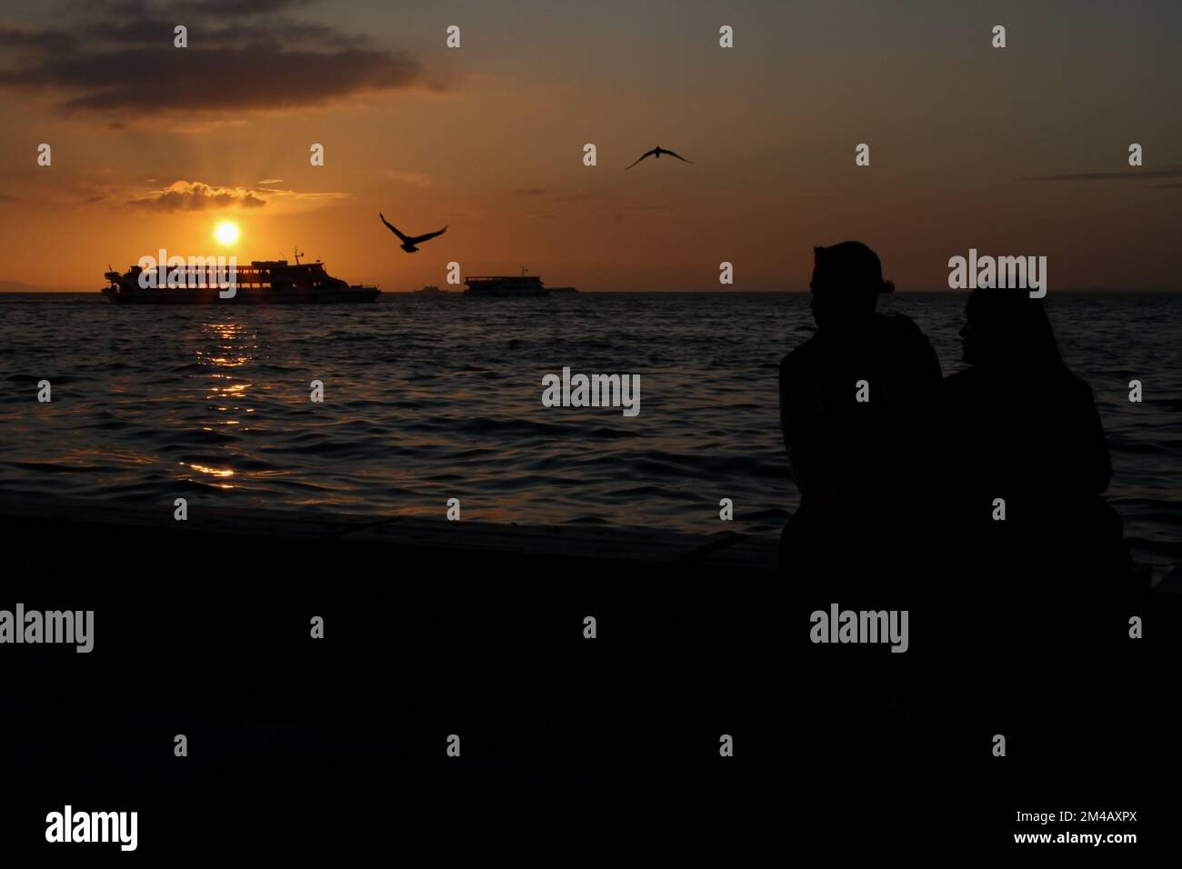 Silhouettes de bateaux à vapeur turcs à İzmir avec mouettes au coucher du soleil doré. Coucher de soleil à İzmir Kordon Banque D'Images