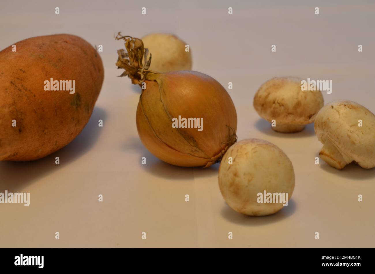 Légumes en vrac sur fond blanc. Pomme de terre, oignon, champignons. Photo. Banque D'Images