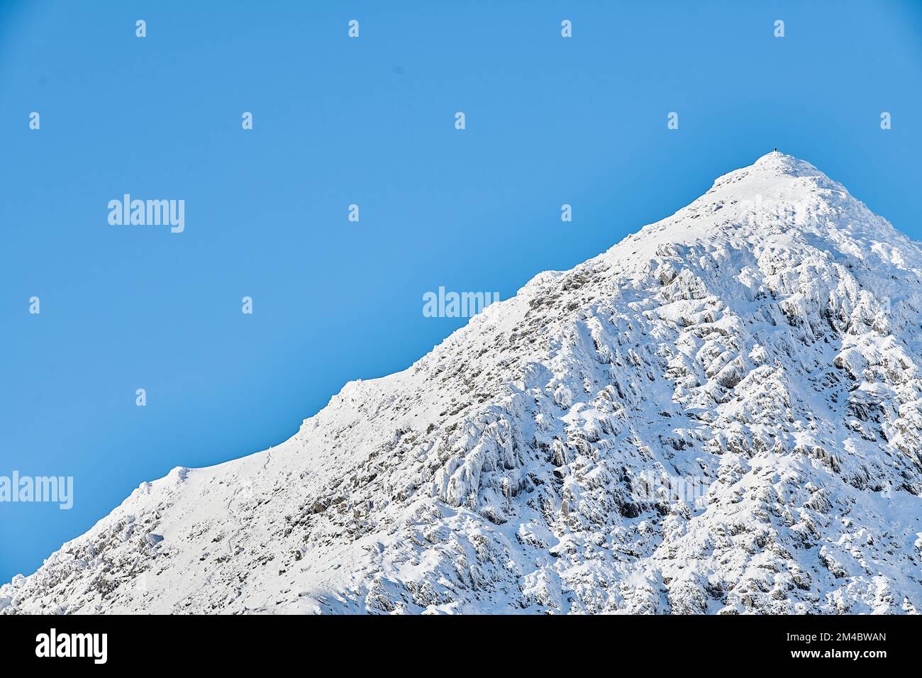 Une personne solitaire au sommet du mont Snowdon pendant une journée d'hiver ensoleillée. Banque D'Images