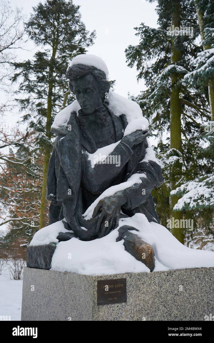 Statue de bronze moulée de Frédéric Chopin par Józef Gosławski dans le parc de naissance de Chopin à Żelazowa Wola en Pologne est couverte de neige. Banque D'Images