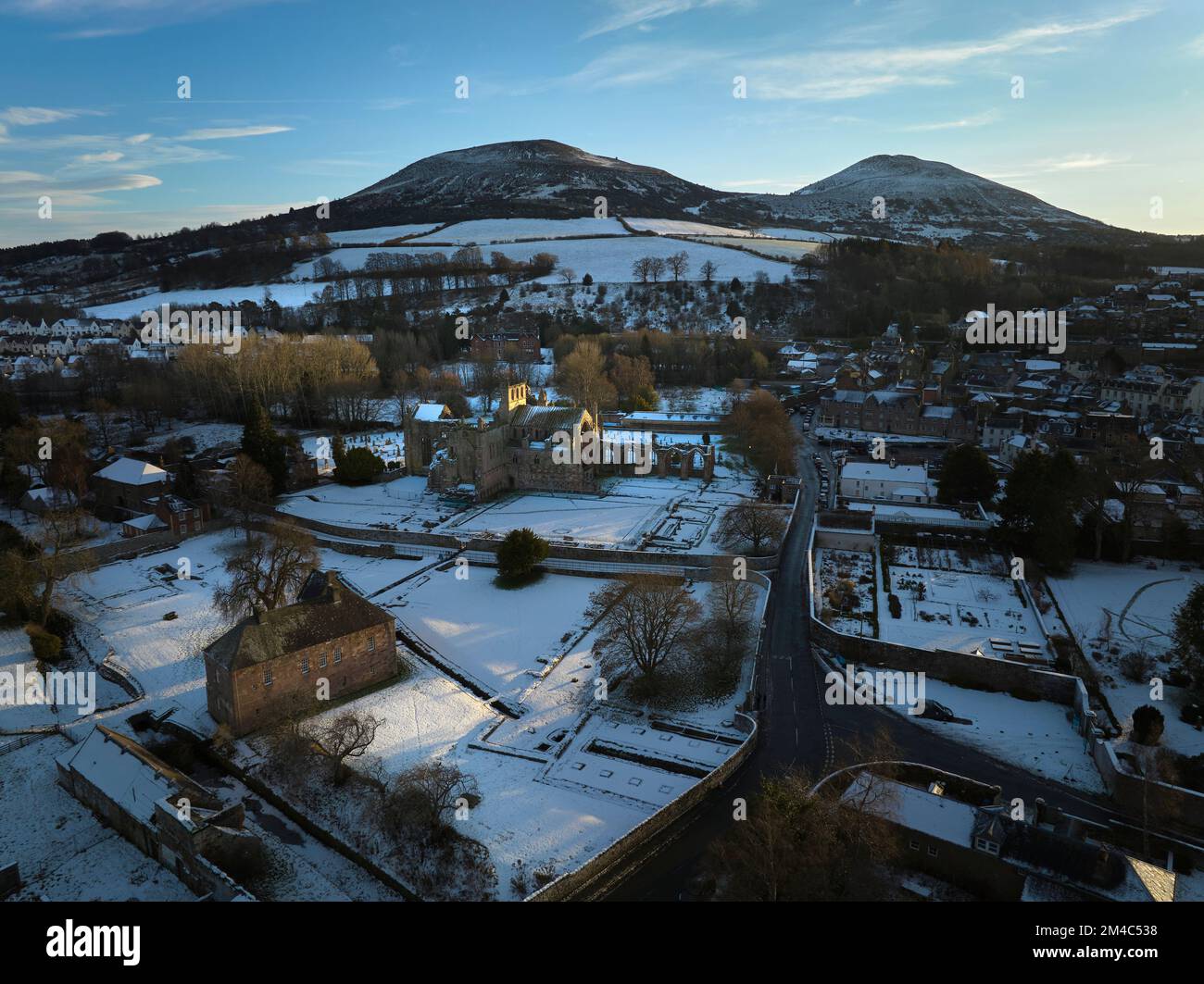 Prise de vue aérienne de l'abbaye de Melrose et des Eildons avec une couche de neige et de gel au coucher du soleil, par une belle journée d'hiver en décembre. Banque D'Images