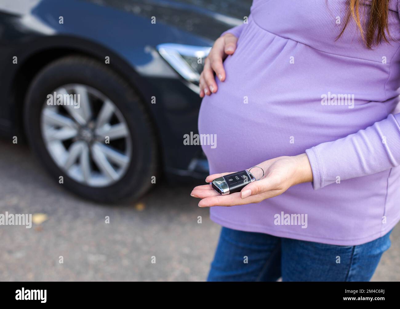 Une fille enceinte avec un gros ventre tient une clé de voiture dans sa  main. Connu pour les dangers de conduire une voiture pendant la grossesse,  la menace de fausse couche. TRAV