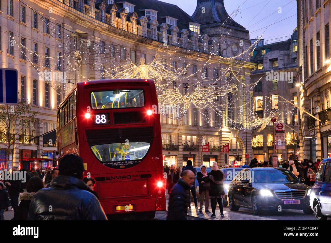 Regent Street, Londres - une foule de clients qui se prominent entre les grands magasins éclairés et le trafic de vacances sous les lumières de Noël Banque D'Images