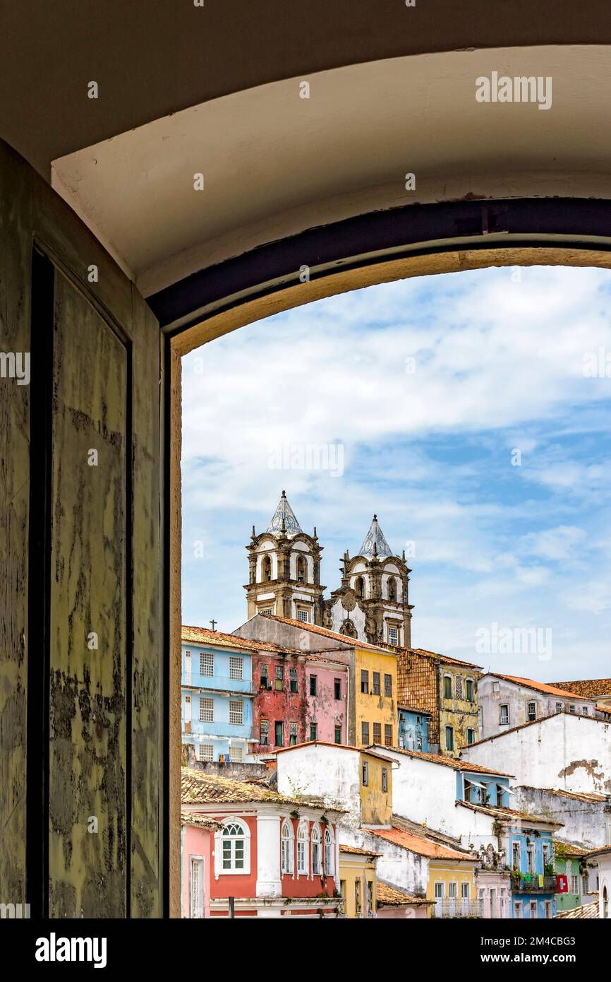 Vue sur le célèbre quartier de Pelourinho dans la ville de Salvador à travers une ancienne fenêtre en bois de style colonial Banque D'Images