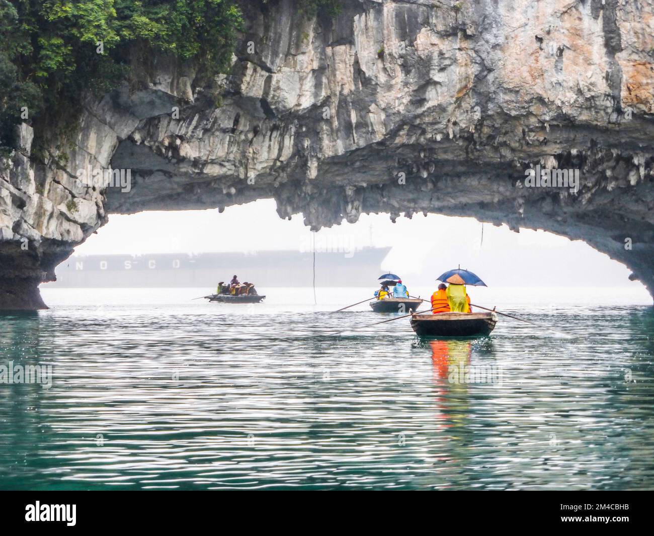 Une vue des touristes profiter de la navigation en bambou autour de la grotte de Luon, île de Bo Hon au Vietnam, un jour pluvieux, avec un navire dans le fond brumeux Banque D'Images