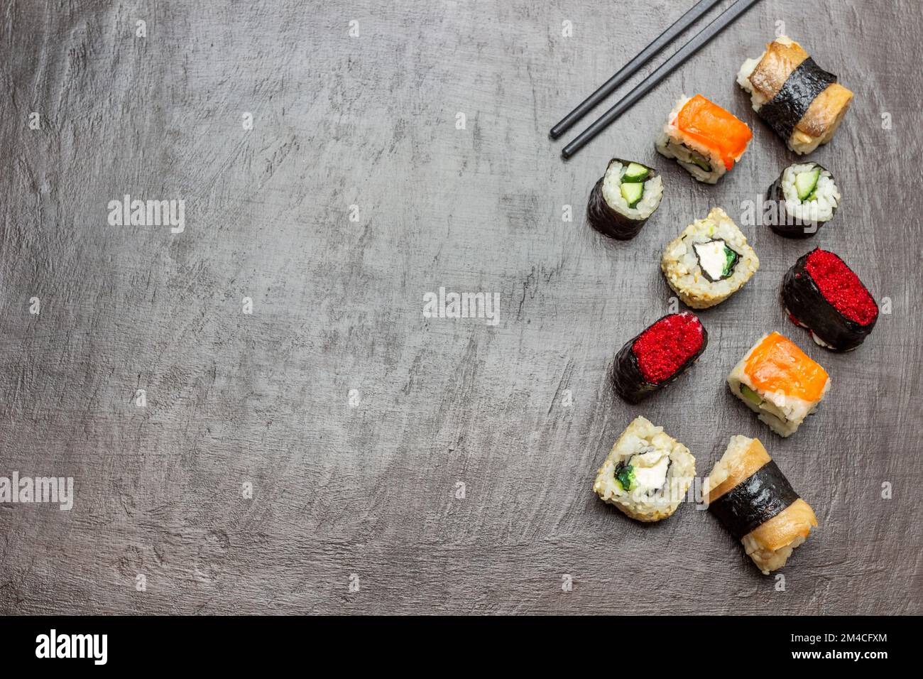 Sushi de différents types. Copier l'espace. Pose à plat. Baguettes noires. Arrière-plan marron. Banque D'Images