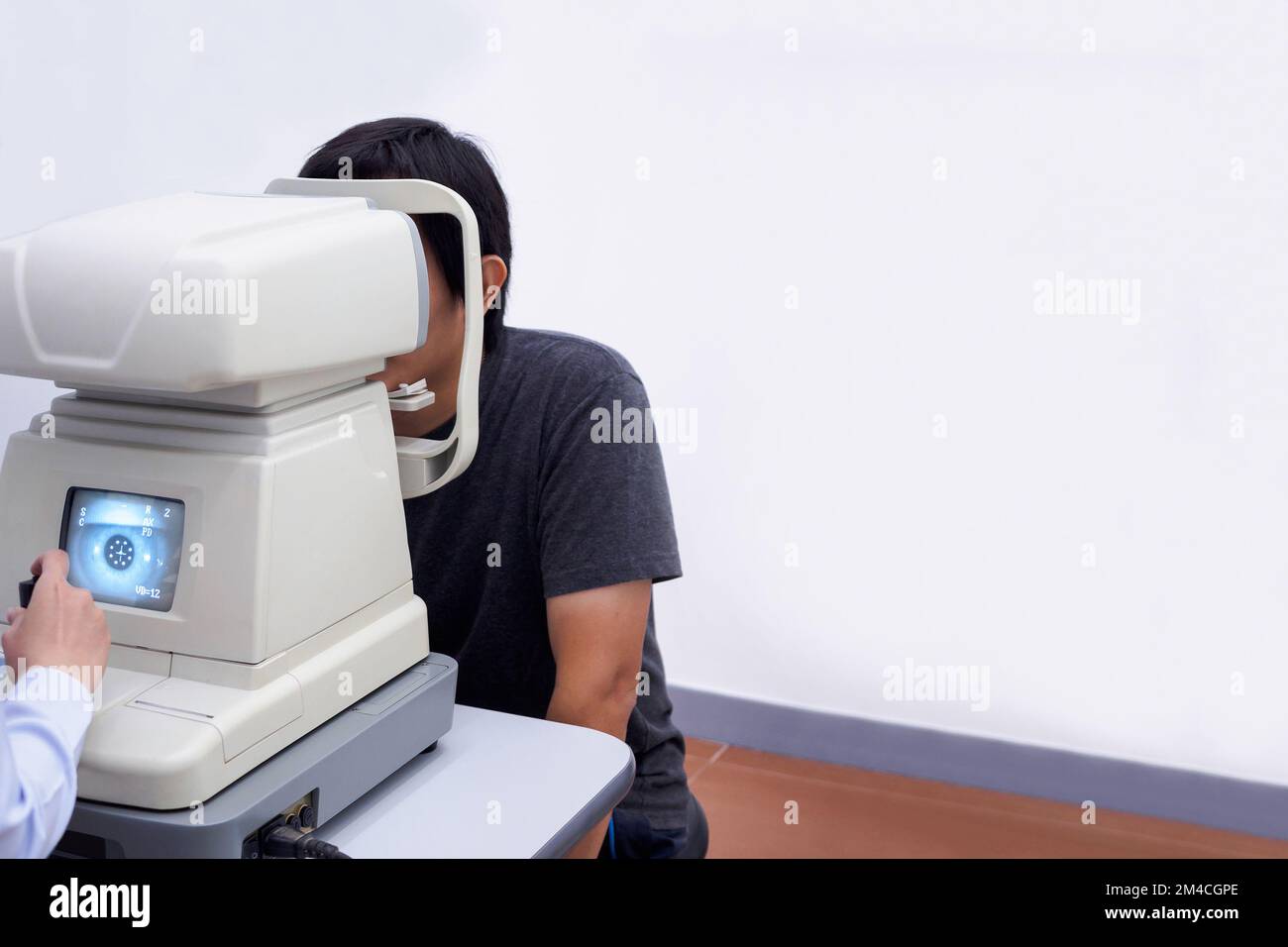 Un jeune homme asiatique élégant se fait un examen visuel avec une machine de test optique Banque D'Images