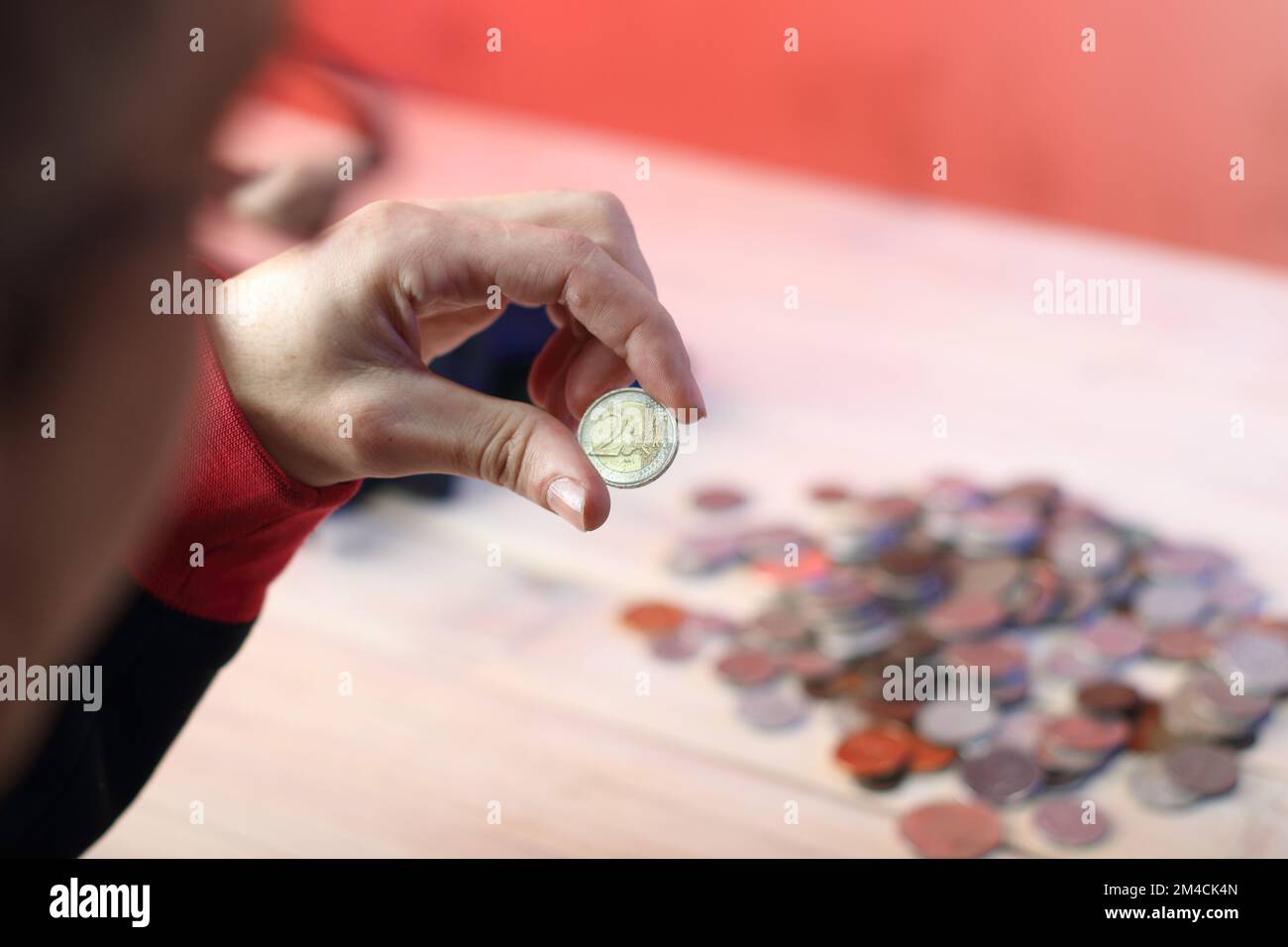 coin deux euros dans les doigts contre le fond d'une table avec des pièces Banque D'Images