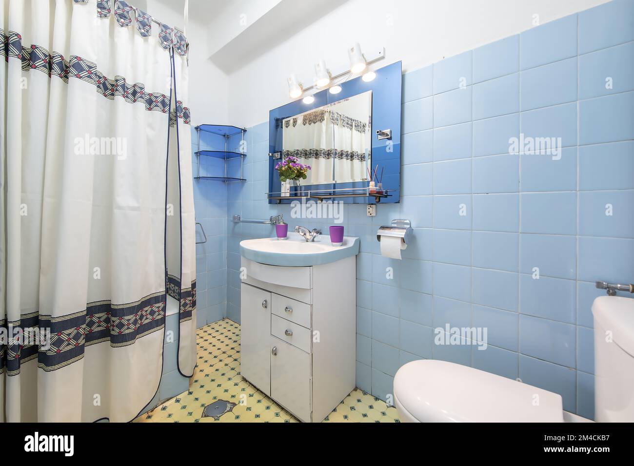 toilettes anciennes avec armoire blanche avec évier en porcelaine bicolore,  sols d'époque, miroir bicolore avec spots et rideaux de douche dans la  baignoire Photo Stock - Alamy