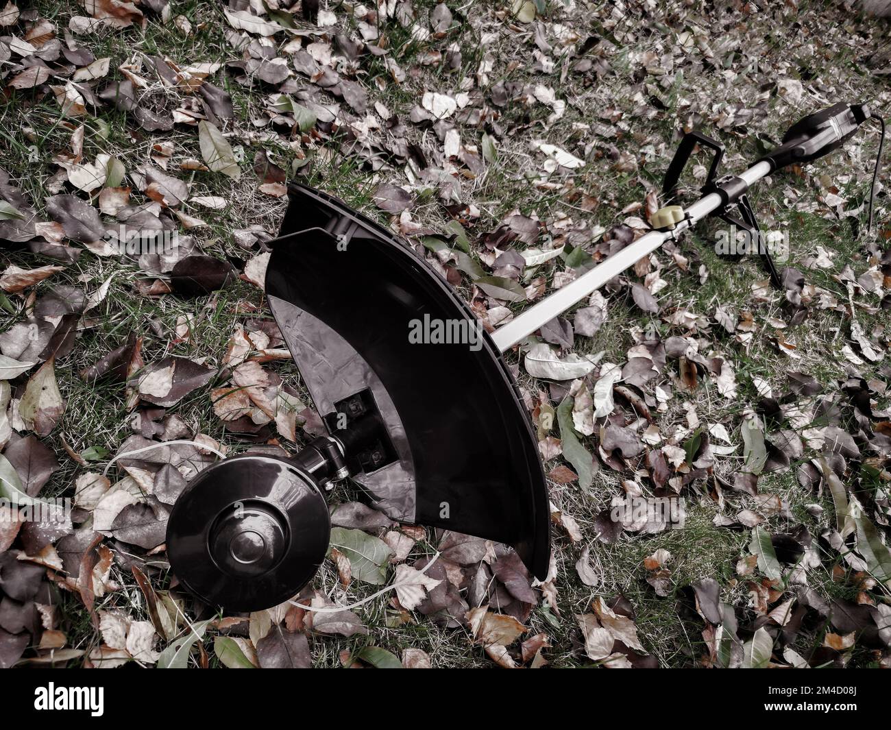 Appareils ménagers: Tondeuse-tondeuse pour tondre les pelouses . Présenté sur un fond d'herbe et de feuilles, vue de face, espace de copie Banque D'Images
