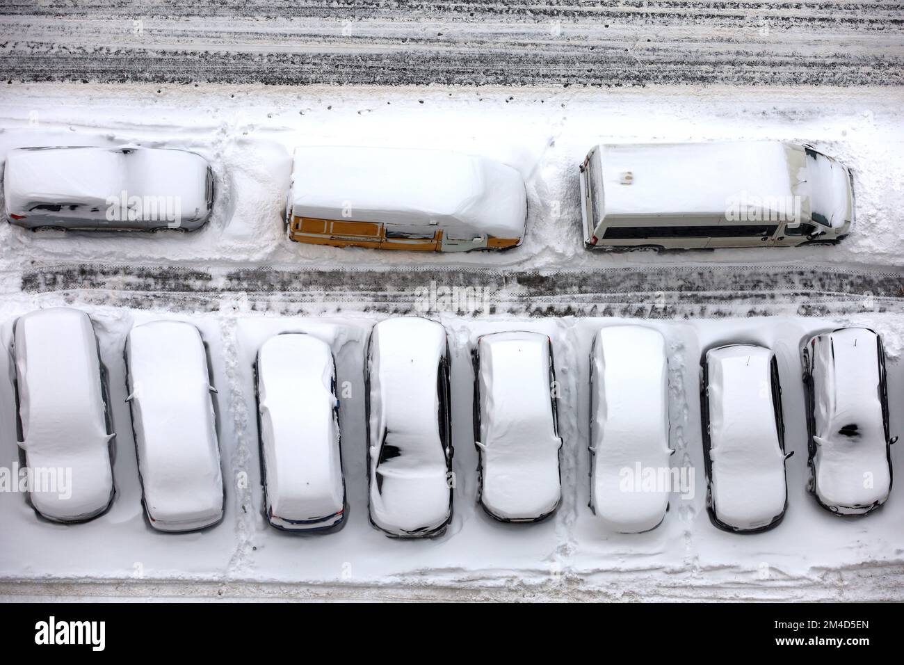 Vue sur les voitures de suite sur un parking couvert de neige, vue de dessus. Chute de neige dans une ville Banque D'Images