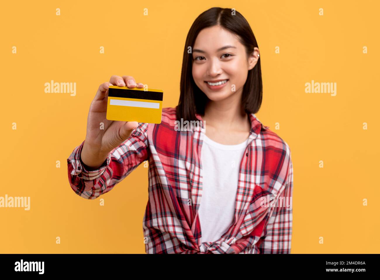 Bonne dame coréenne montrant la carte de crédit, le service de banque de publicité sur fond jaune de studio, selevtive focus Banque D'Images