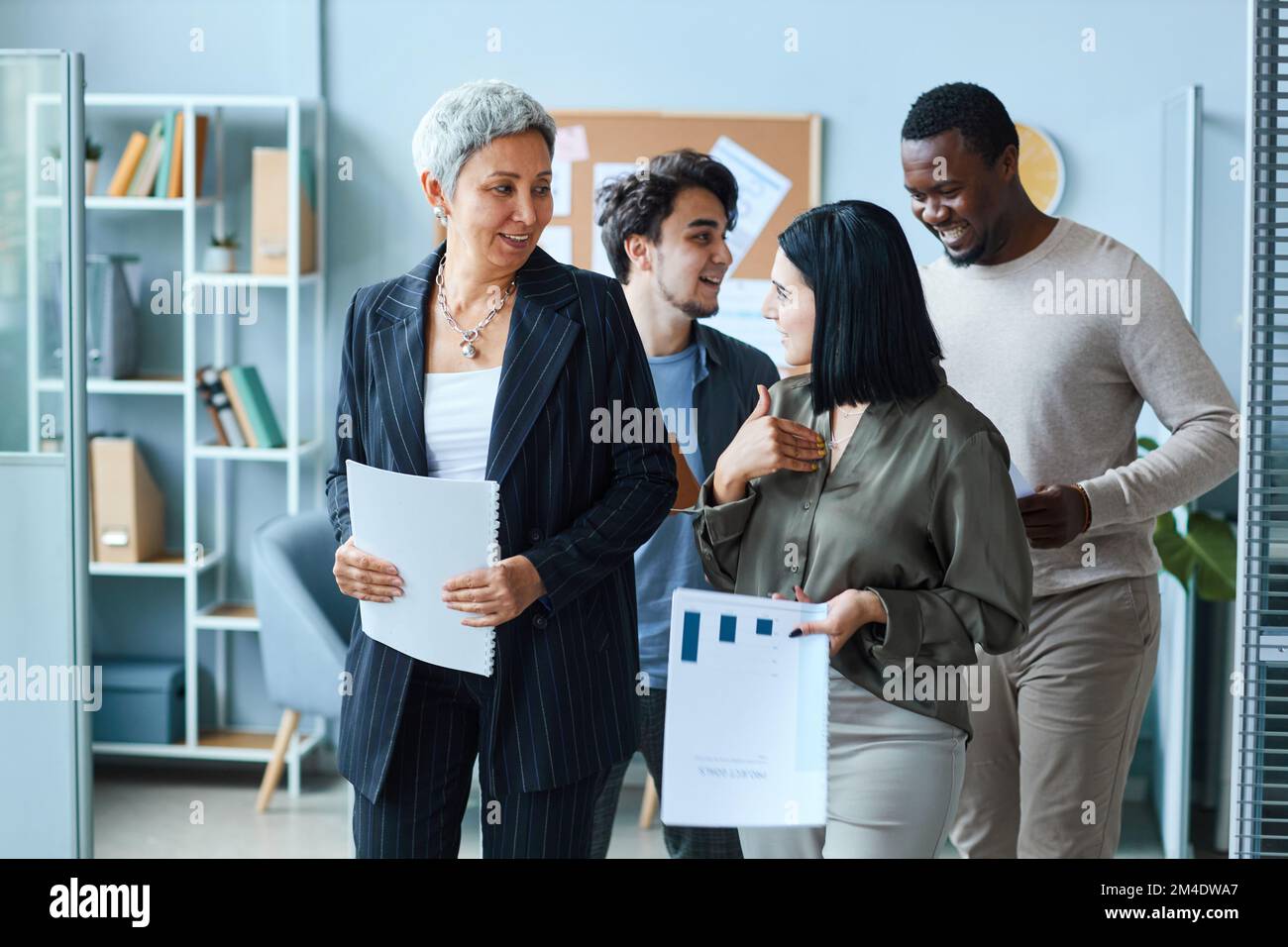 Groupe multiethnique de gens d'affaires joyeux avec une femme patron en direction de l'appareil photo au bureau Banque D'Images