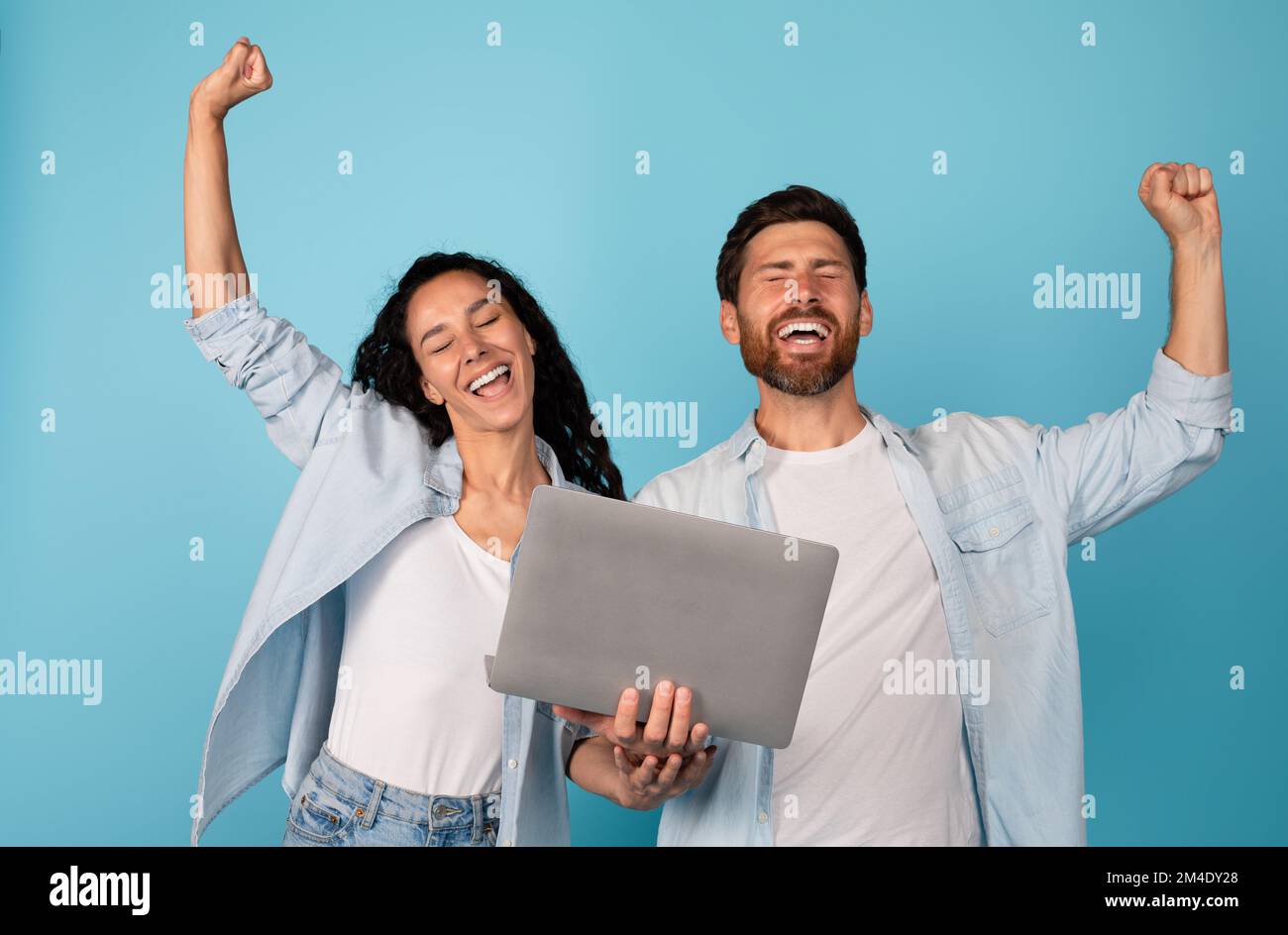 Un jeune couple européen plein d'émotions satisfait avec un ordinateur portable fait un geste de réussite et de victoire, profitez de gagner ensemble Banque D'Images
