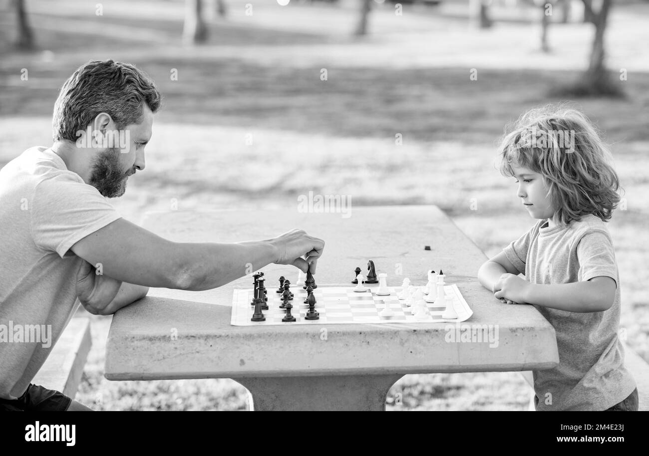 famille heureuse de père et de fils enfant jouant aux échecs sur la table dans le parc extérieur, logique Banque D'Images
