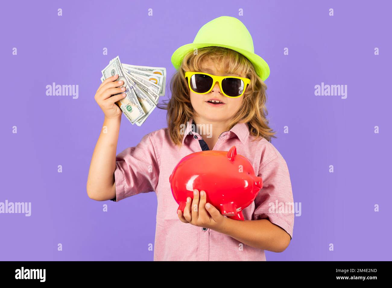 Concept argent et piggybank. Portrait d'un petit garçon mettant de l'argent sur une moneybox. Un enfant économisant de l'argent dans une porcgybank en arrière-plan. Banque D'Images