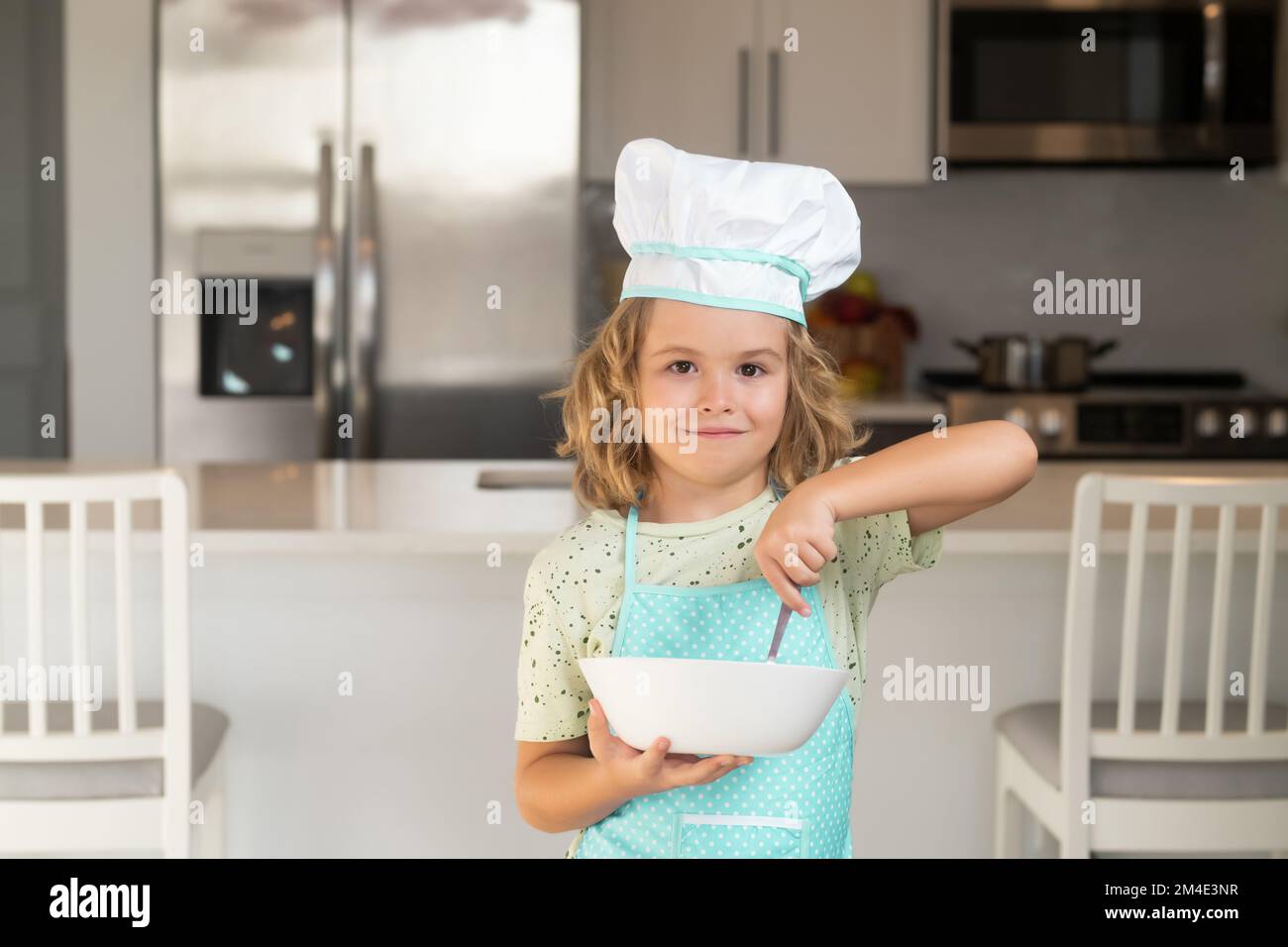 Cuisinier enfant avec plaque de cuisson. Chef enfant garçon cuisant sur la cuisine. Le chef cuisinier prépare la nourriture en cuisine. La cuisine des enfants. Adolescent avec tablier Banque D'Images